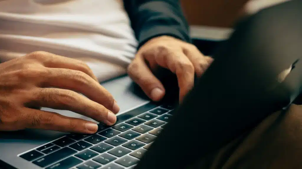 Imagem de uma pessoa mexendo em um notebook preto, em alusão a uma consulta de placa na web