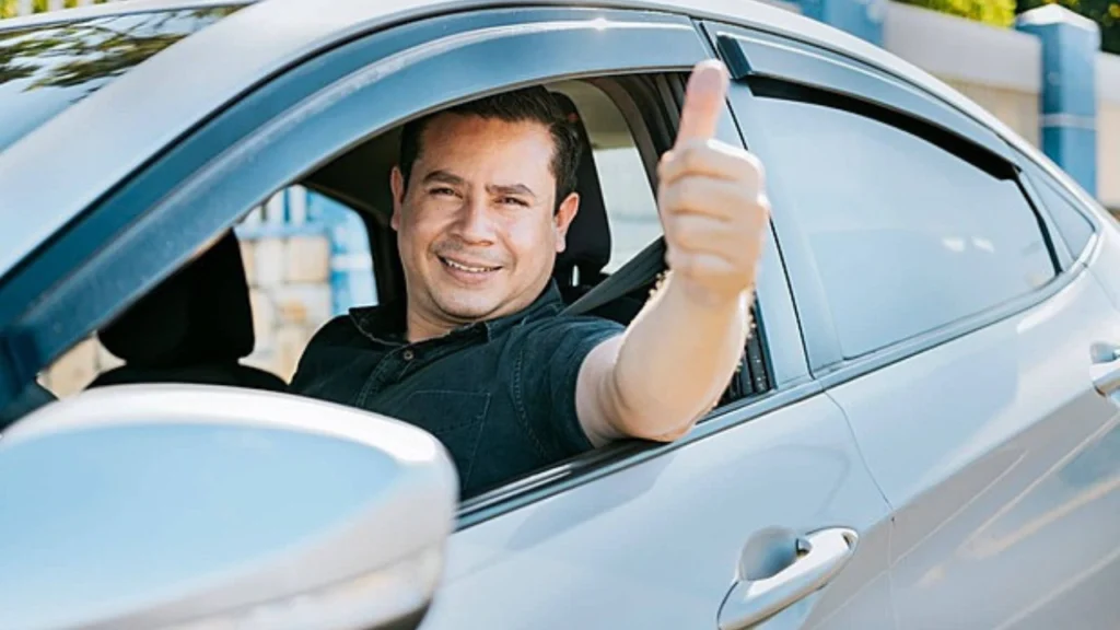 Foto de pessoa feliz com seu carro e fazendo sinal positivo