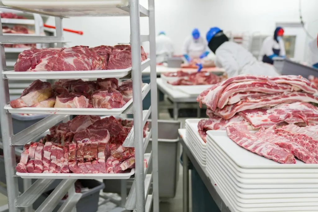 Bandejas com cortes de carne bovina organizadas em prateleiras industriais.
