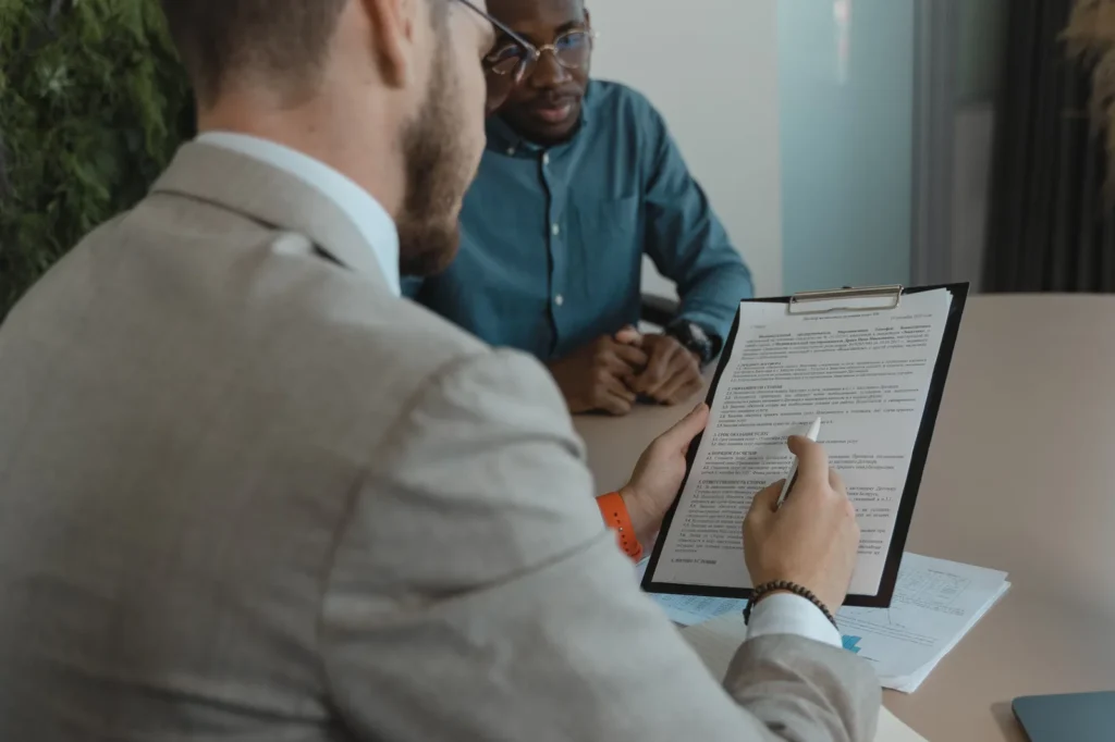 Homem de terno revisando contrato de distribuição com uma prancheta em reunião.