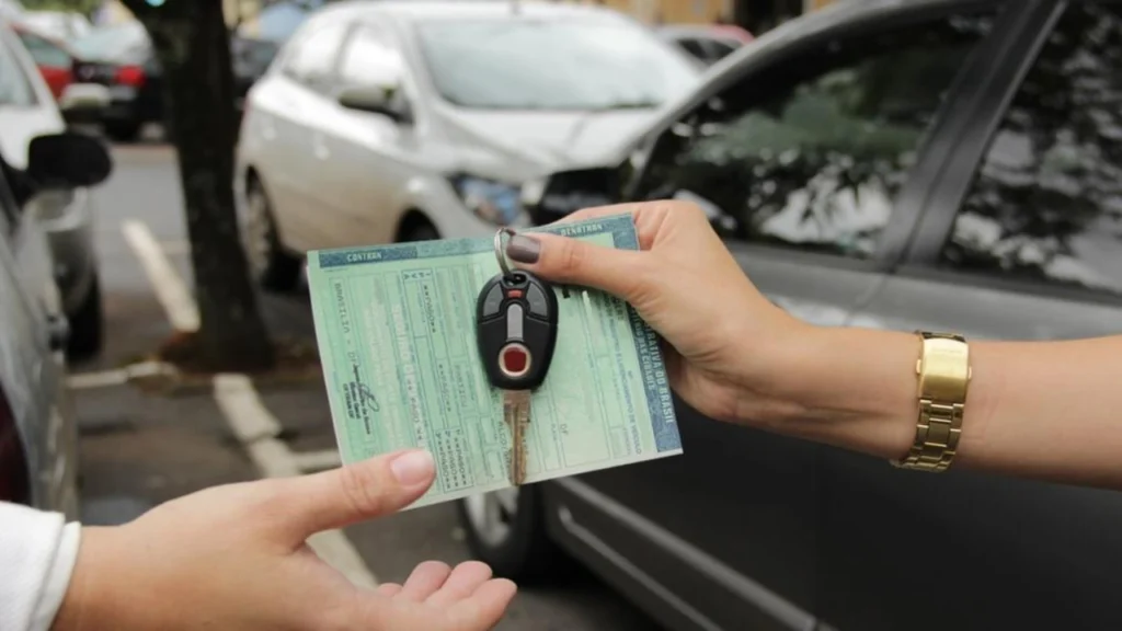 Foto de uma mulher entregando a chave e os documentos de um carro para um homem em alusão a pauta "Adeus à papelada? Transferência de veículos pelo celular ganha força em 2026"!