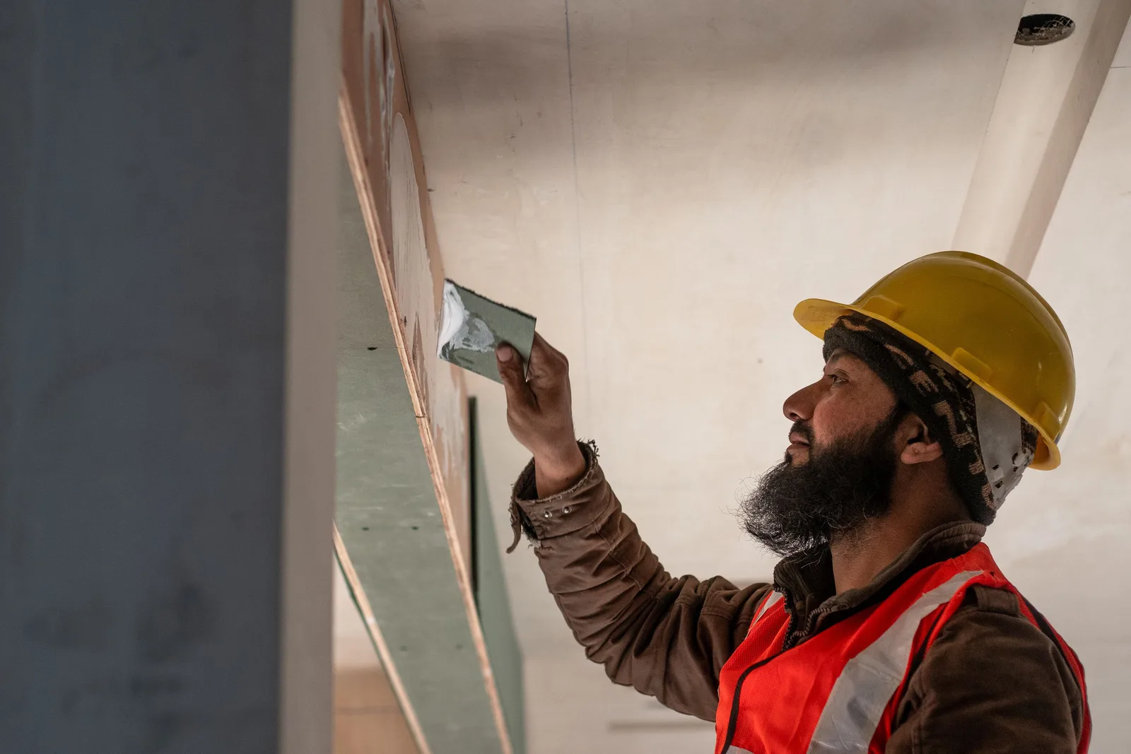 profissional aplicando impermeabilização em parede de obra de construção civil