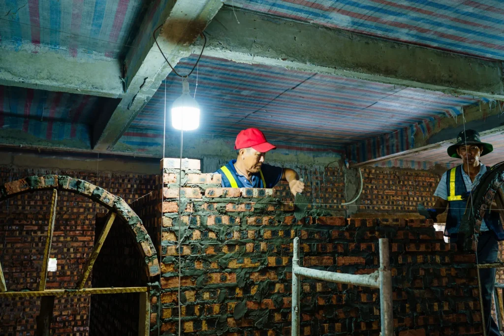 Pedreiro aplicando piso cerâmico em obra de construção civil