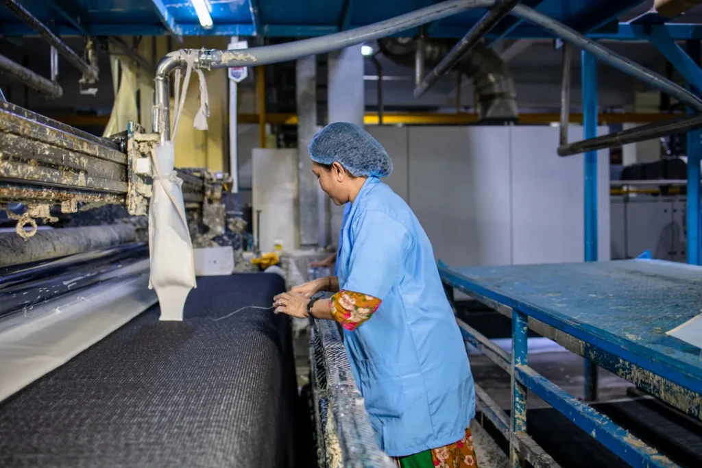 Profissional trabalhando com estamparia e texturização de tecidos em uma fábrica têxtil