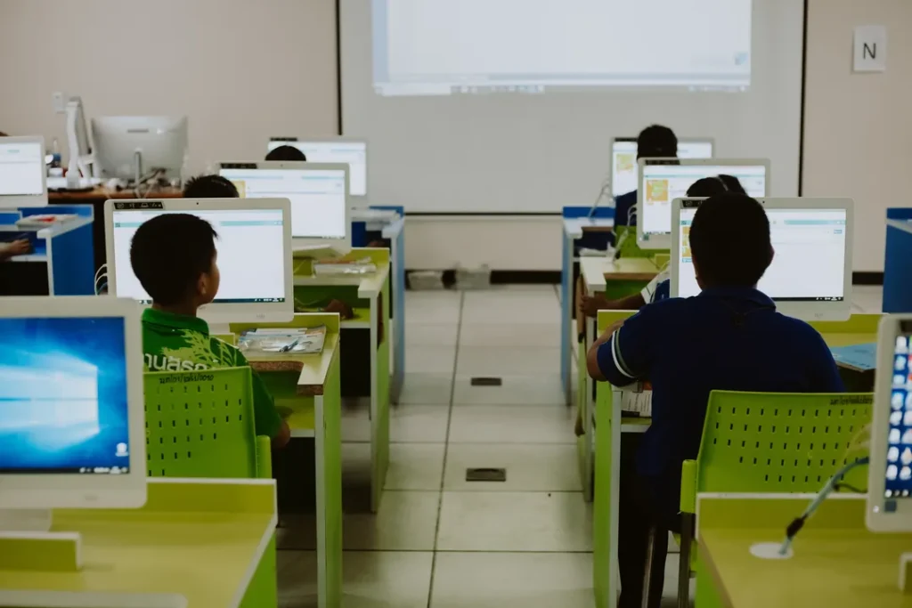 Aluno assistindo aula de informática em laboratório com computadores