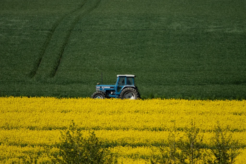 Trator moderno em uma plantação com campo agrícola ao fundo