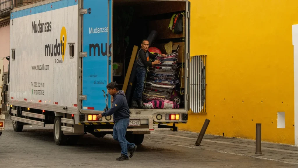 Caminhão de mudança carregando caixas de papelão e móveis em uma rua