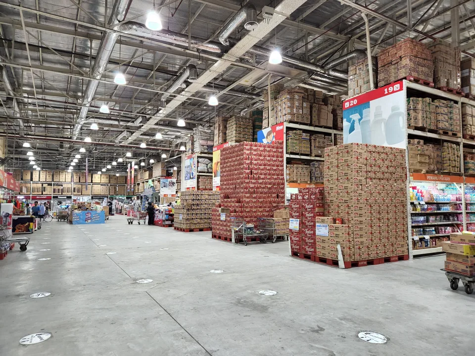 Galpão de distribuidora com caixas e luminárias sendo organizadas para comércio atacadista
