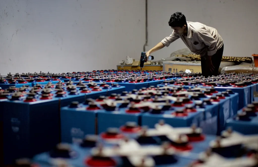 Trabalhador em uma fábrica industrial produzindo baterias para automóveis