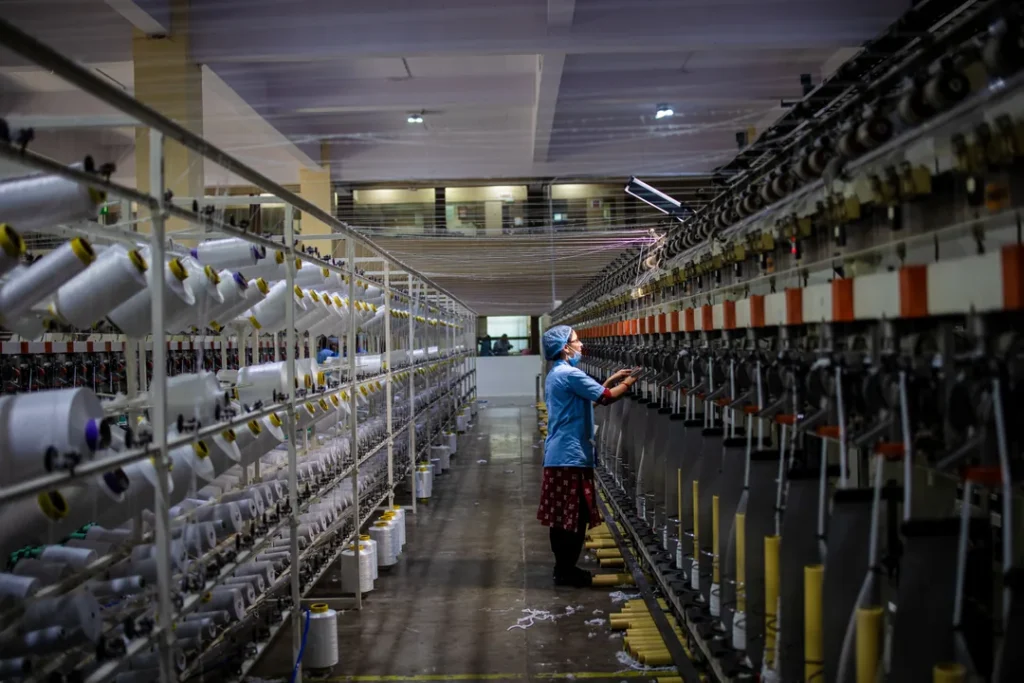Trabalhador industrial operando maquinário de fiação de fibras têxteis naturais em uma fábrica
