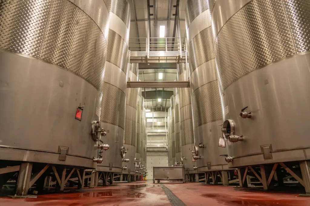 Linha de produção de bebidas em fábrica com garrafas e tanques industriais