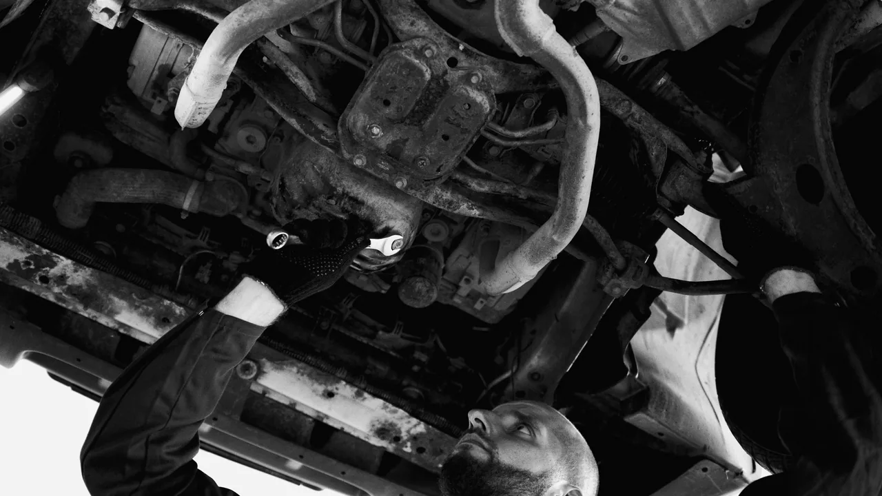 Mecânico inspecionando a parte de baixo de um carro